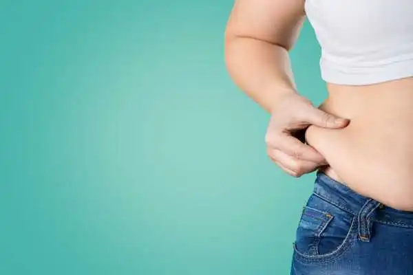 Image of woman pinching her love handles to show weight gain Halstead