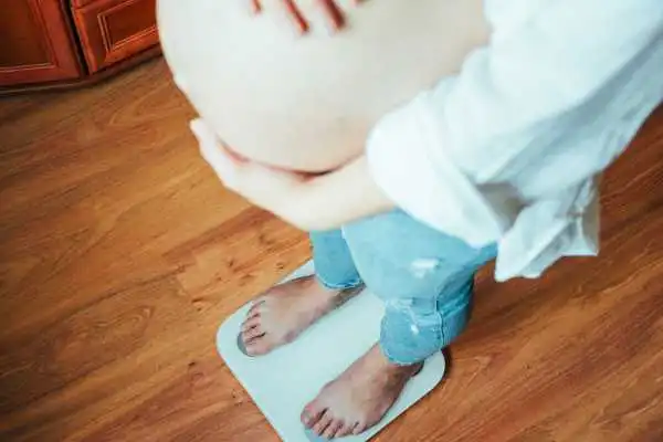 Image of woman weighing herself and experiencing weight gain through pregnancy Halstead